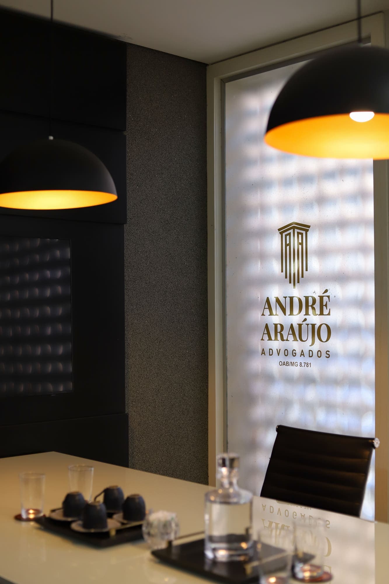 Mesa da sala de reuniões com o logotipo do escritório na parede de cobogós e luminária preta